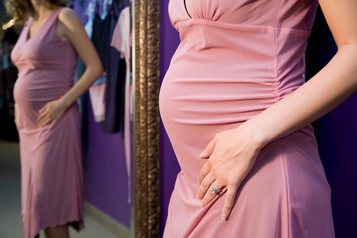Pregnant woman trying on dress in a shop