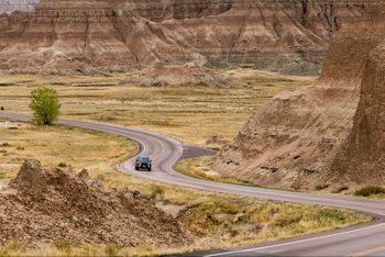 Car Driving along winding road, Badlands National Park, South Dakota, America, USA