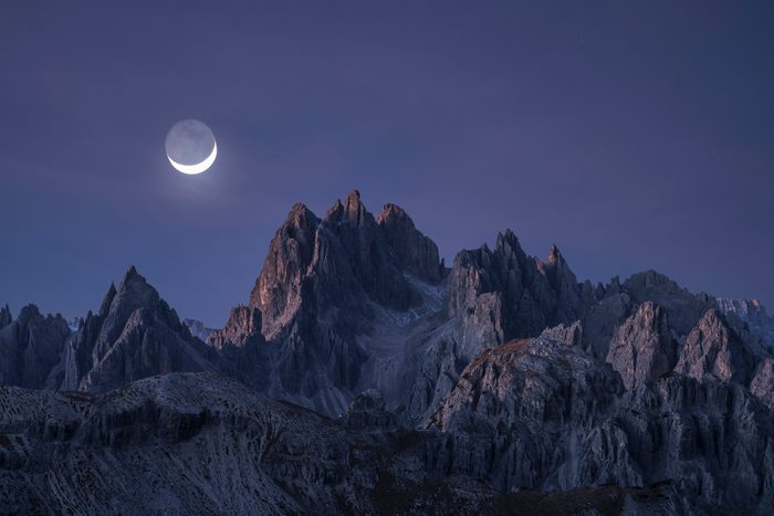 Half moon shining over rocky peaks