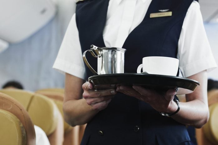 Flight attendant holding tray with coffee