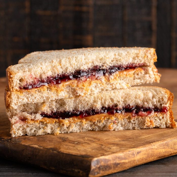 A Peanut Butter and huckleberry jelly Sandwich on a Wooden Cutting Board
