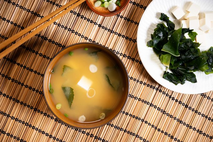Miso soup with tofu and seaweed in brown Japanese bowl