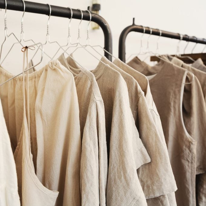 Close up of a selection of clothes in natural colours on a rail in a boutique.