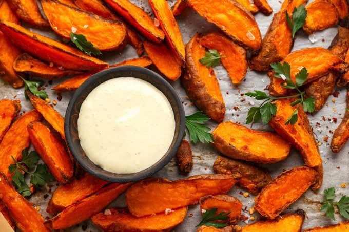 Healthy Baked Orange Sweet Potato wedges with dip sauce, herbs, salt and pepper