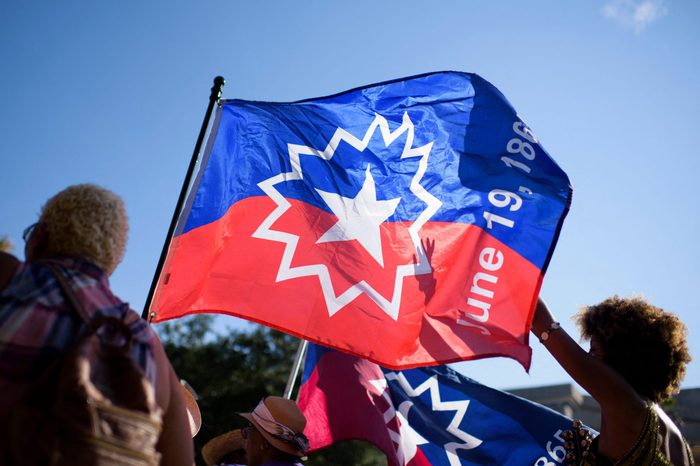 People carry a Juneteenth flag as they march during a Juneteenth re-enactment celebration in Galveston, Texas, on June 19, 2021.