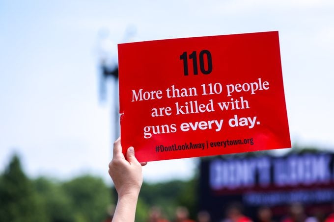 an activists holds up a sign that says "more than 110 people are killed with guns every day" at a rally against gun violence demanding action from lawmakers on June 8, 2022 in Washington, United States.