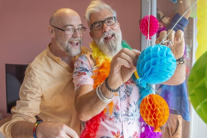 two men decorate their home to celebrate pride with friends