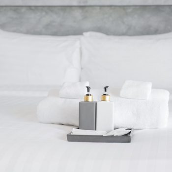 toiletries and clean towels set on a hotel bed