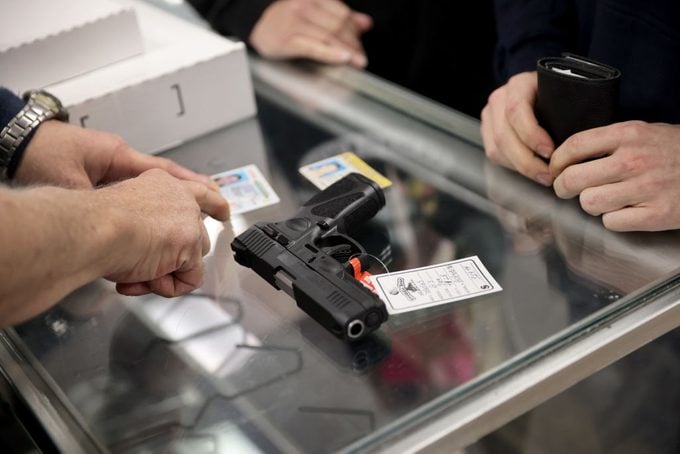 a gun retailer checks the id of a customer