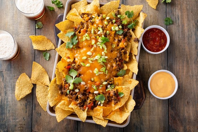 Traditional nachos with ground beef and red pepper served with a side of salsa, cheese and beer