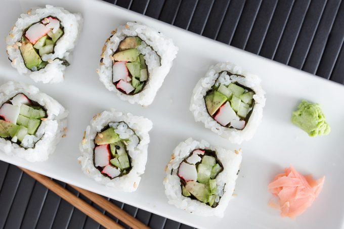 california sushi roll on a white plate with wasabi and ginger