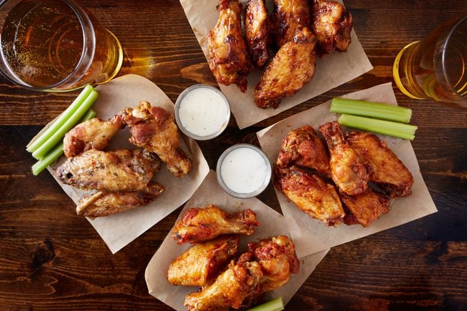 overhead view of four different flavored chicken wings with beer