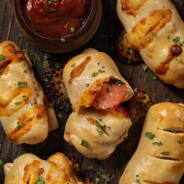 Pepperoni rolls on a wooden board with a side of dipping sauce
