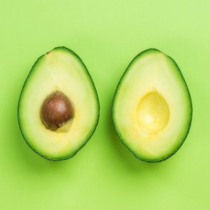 Avocados halves on a green background