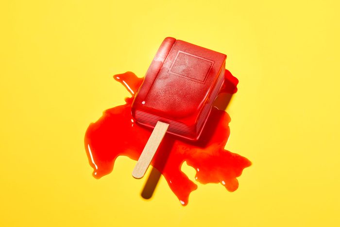 a red popsicle in the shape of a book melts on a yellow background