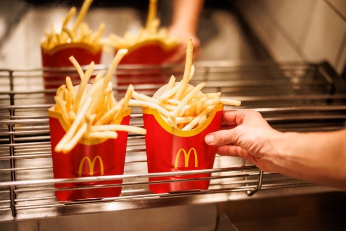 Mcdonald's Employee reaches for large fries sitting under the heat lamp