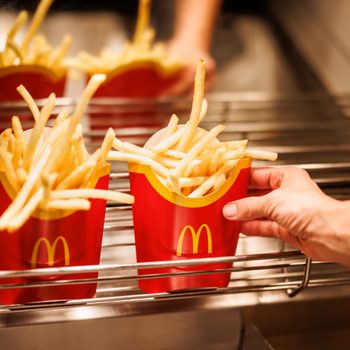 Mcdonald's Employee reaches for large fries sitting under the heat lamp