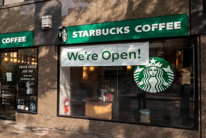 starbucks coffee exterior with a sign on the window that says "we're open!"