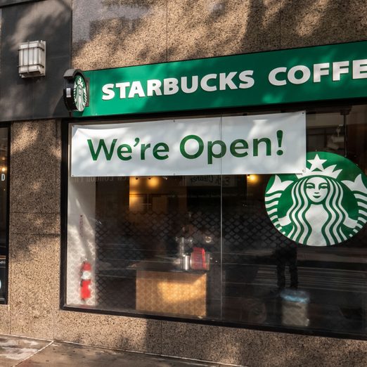 starbucks coffee exterior with a sign on the window that says "we're open!"