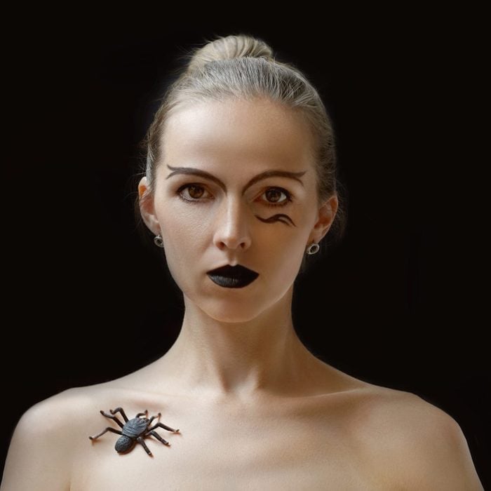 Woman with spider on collarbone close-up.