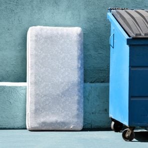 mattress next to a blue recycling bin outside