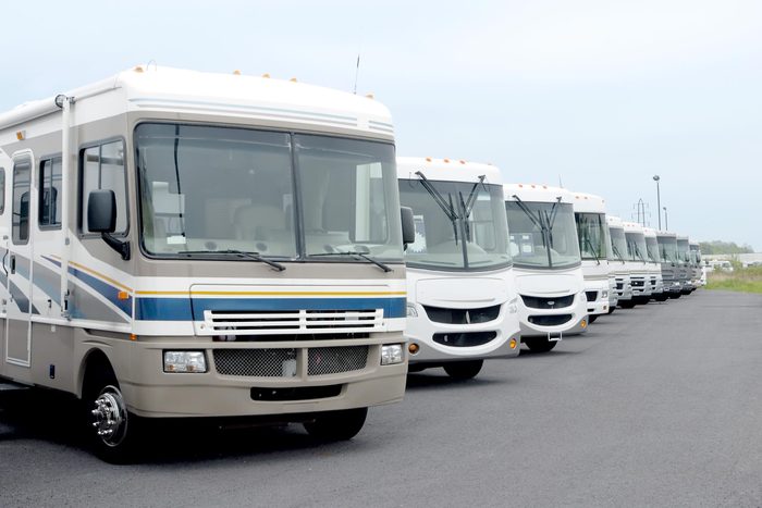 a row of class A motorhomes for sale in a parking lot