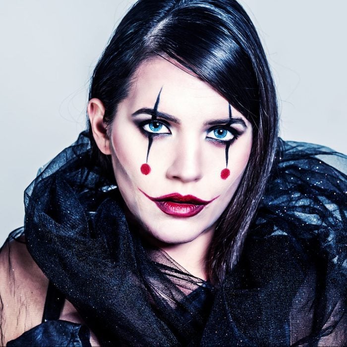 Portrait of young woman with creative make up as joker lady for halloween .