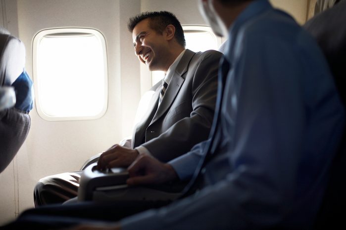Business men sitting in airplane laughing, differential focus