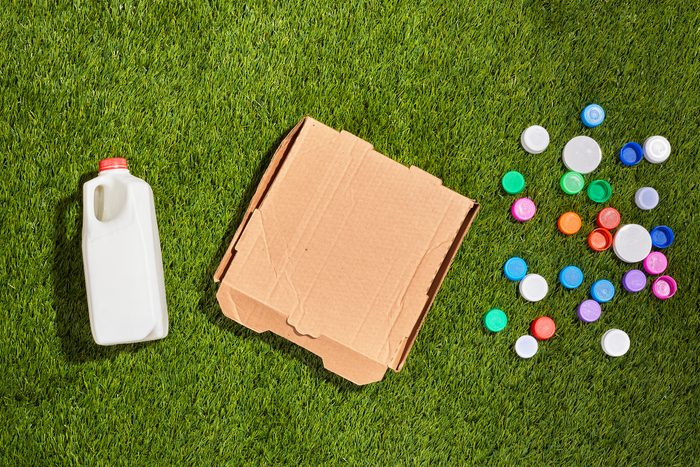 Milk carton, cardboard box, and plastic bottle caps on grass