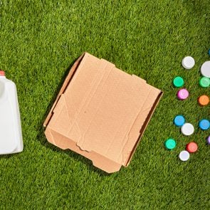 Milk carton, cardboard box, and plastic bottle caps on grass