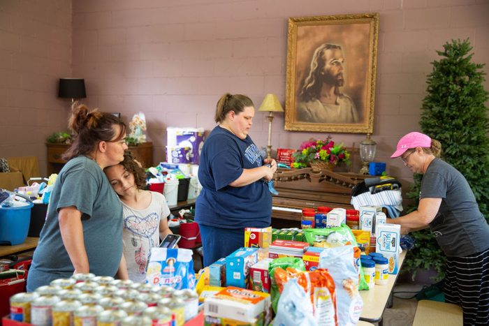 Ashley Smith hugs her daughter Hayllie Smith, 8, while helping organize donations for flood victims at the Saul Communty Center in Saul, Ky