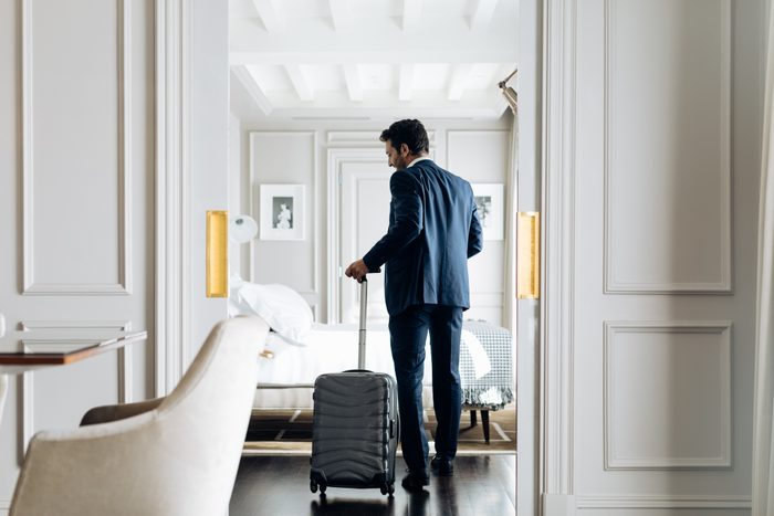Businessman with wheeled luggage in a hotel suite