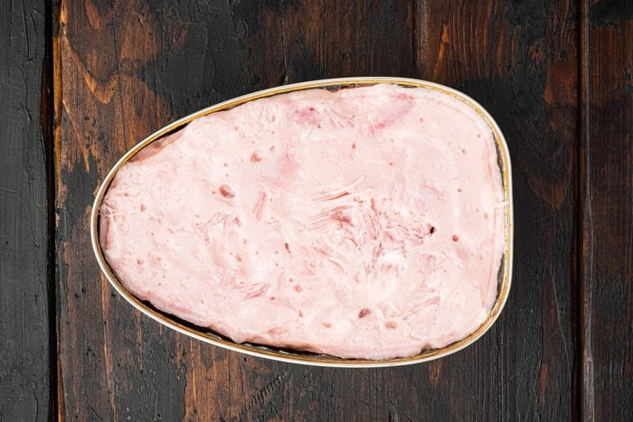 Canned food, luncheon meat ham, on old dark wooden table background, top view flat lay