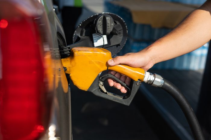Mans's hand holding fuel nozzle in car