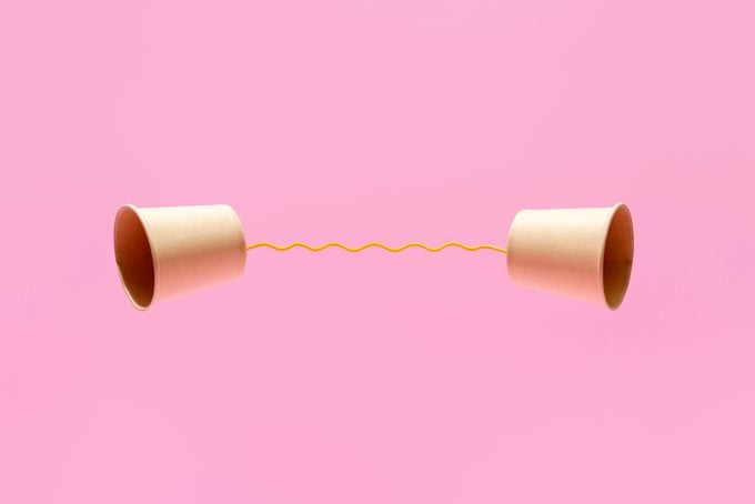 Two Paper Cups United With A Yellow String On A Pink Background