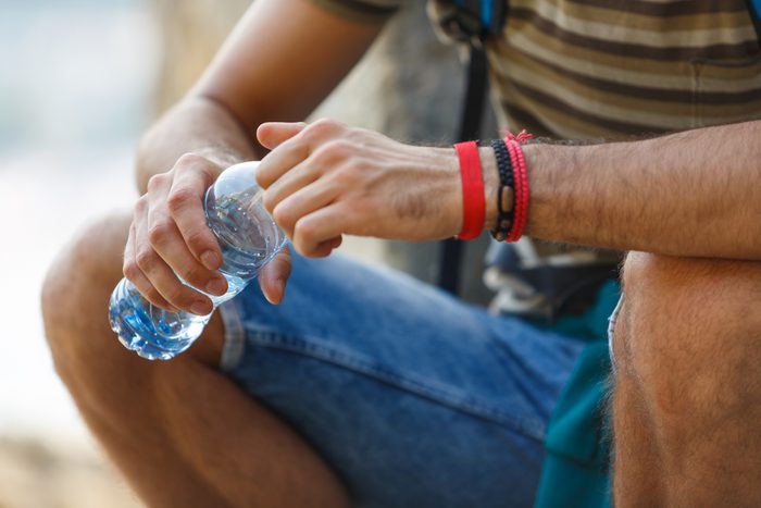 close up of a man's hands holding a plastic water bottle