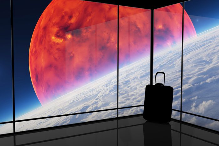 silhouette of a suitcase is a corner with large windows. outside the windows is a view of plants in outer space.