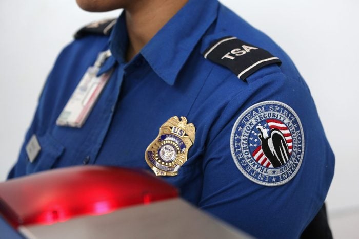 close up of a woman working at an airport in a TSA uniform highlighting the badge on her chest and the patch on her arm