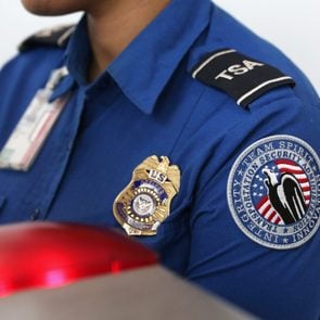 close up of a woman working at an airport in a TSA uniform highlighting the badge on her chest and the patch on her arm