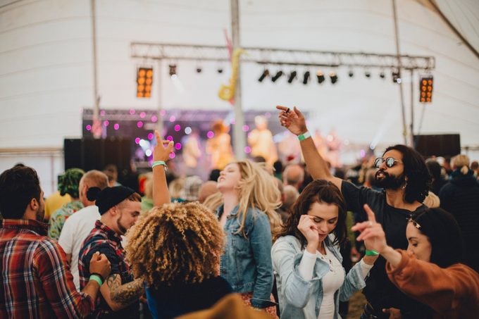 Group of friends dancing together in a marquee at an outdoor music festival.