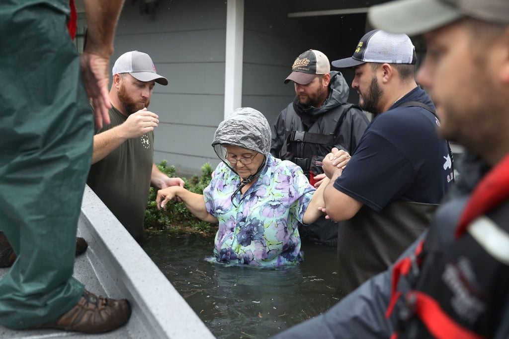 Volunteer rescuer workers help a woman from her home that was inundated with the flooding of Hurricane Harvey on August 30, 2017
