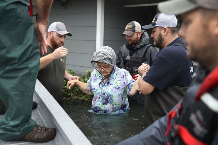 Volunteer rescuer workers help a woman from her home that was inundated with the flooding of Hurricane Harvey on August 30, 2017
