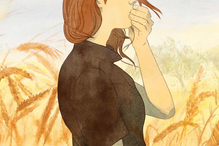 Woman holding mouth against wheat landscape
