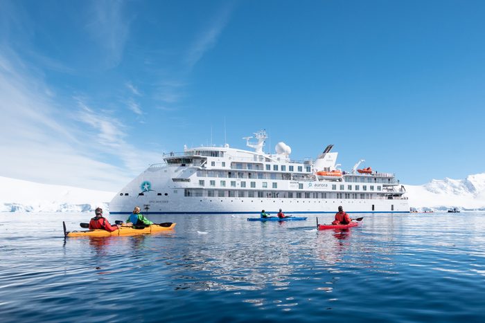 cruise ship with kayakers in front, snowy landscape in the background