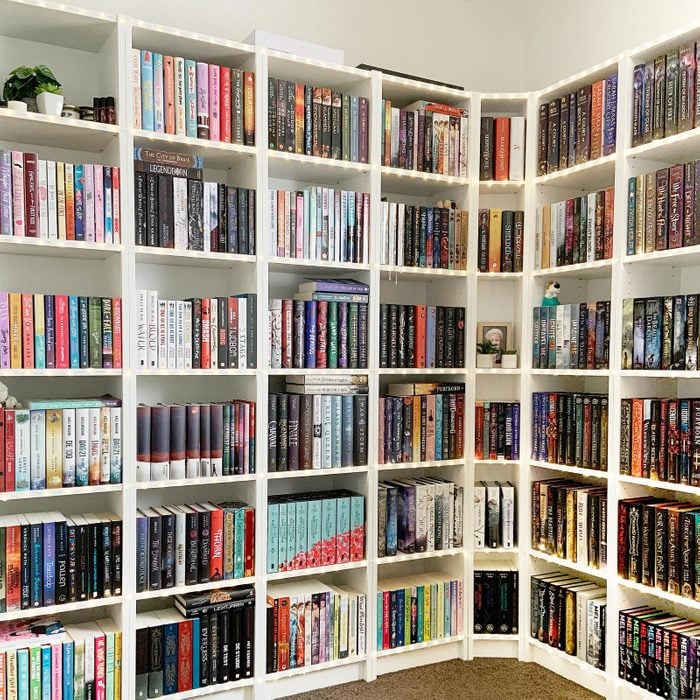 a room with a white wrap around bookcase filled with books in a very organized way