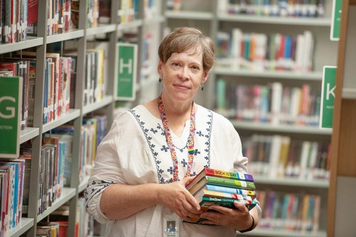 portrait of Martha Hickson standing in a library holding a stack of books