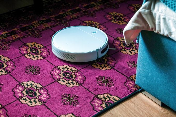 Robot Vacuum on a purple rug in a living room near a blue couch