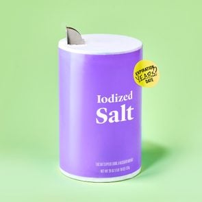 container of salt against green background. the container has an expiration sticker on it.