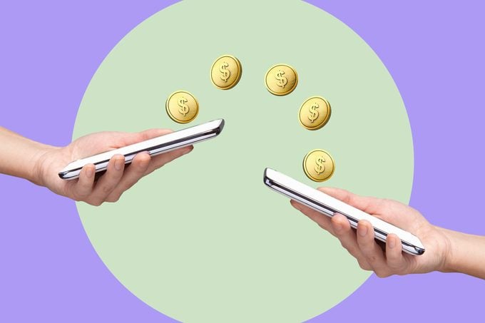 Digitally generated coins with US dollar signs between 2 smart phones in women's hands on circular green background