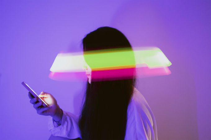 woman using smartphone surrounded by light exposure